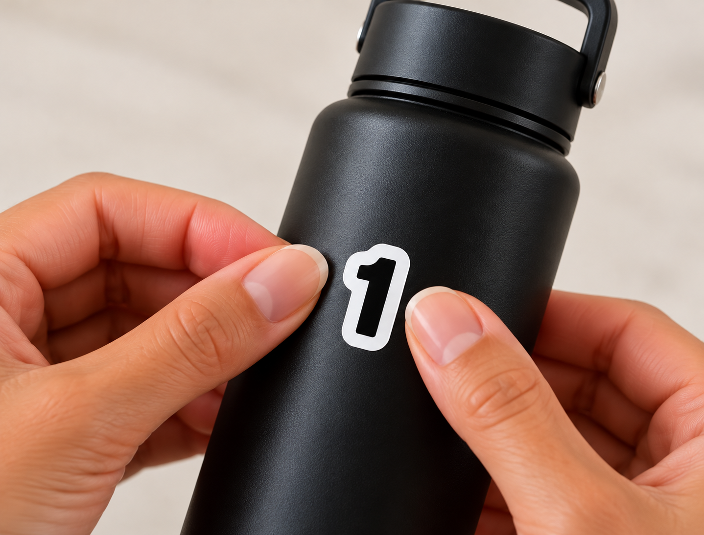 Hands applying the number 1 sticker onto a water bottle